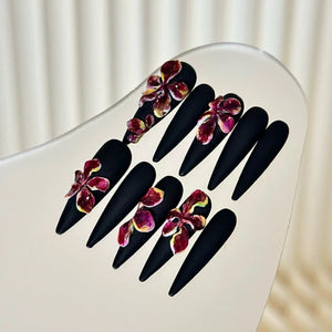 Versatile and stylish black stiletto nails with floral embellishments.