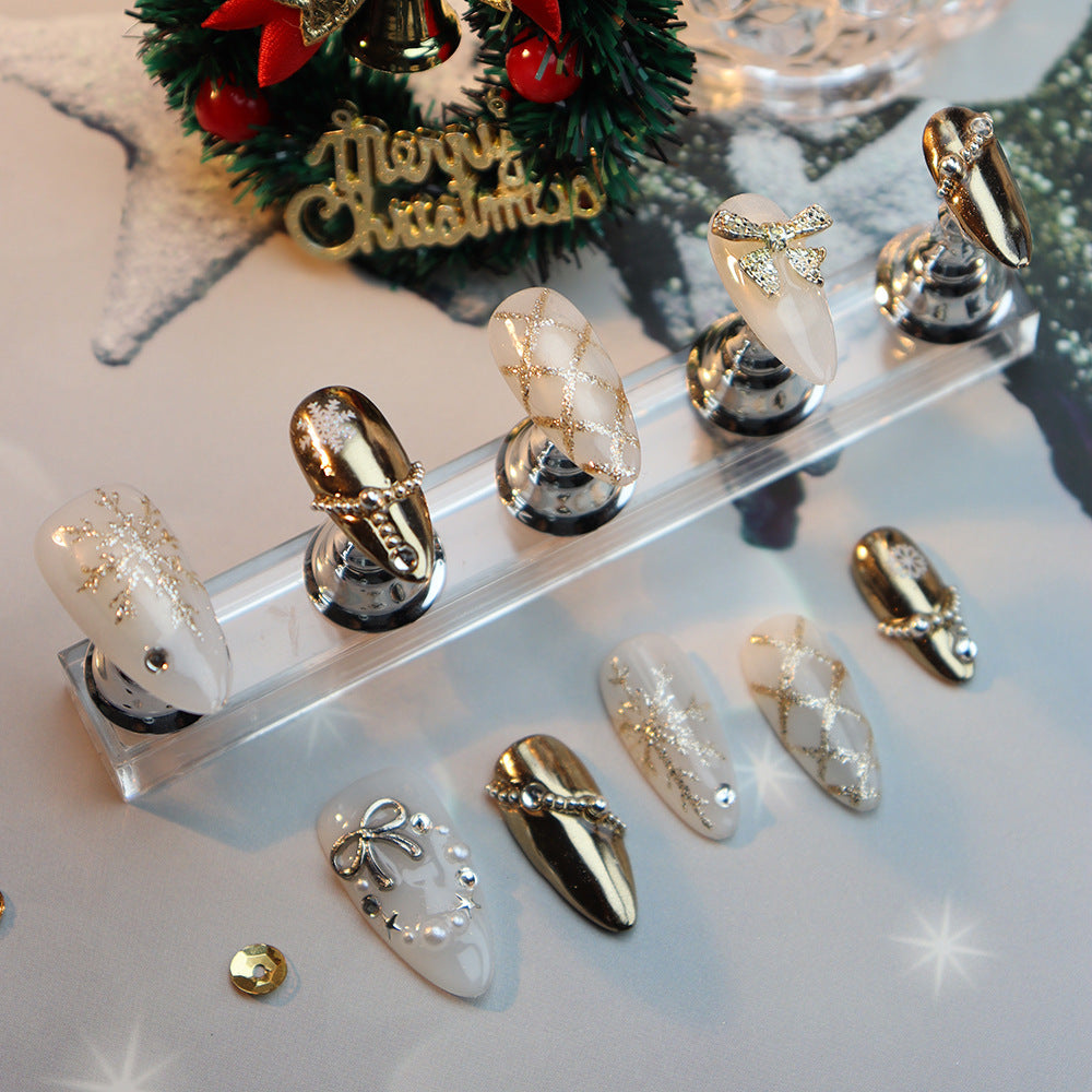 Gold and white oval nails with snowflake patterns and metallic bows.