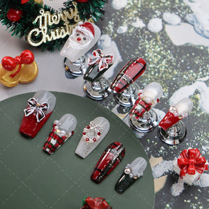 Oval-shaped nails featuring a festive red plaid and bow details.