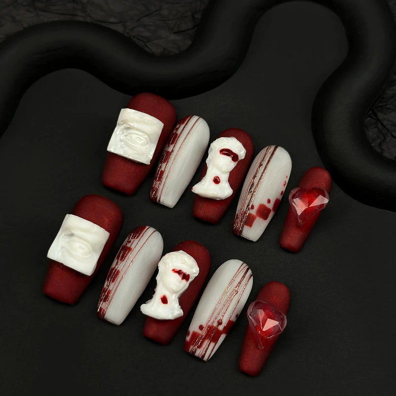 Matte red and white gothic nails featuring intricate 3D art.