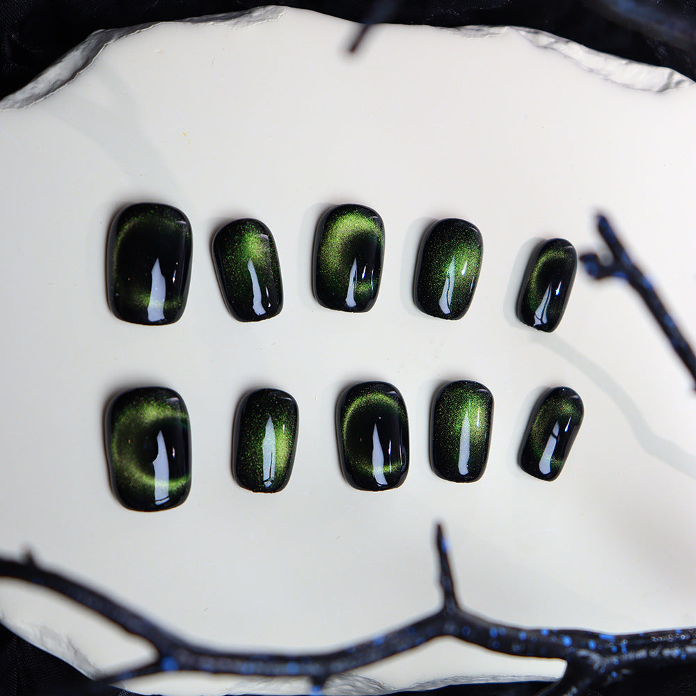 Handcrafted green cat-eye nails displayed neatly.