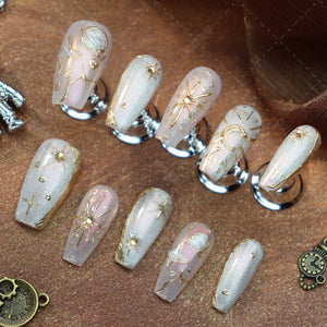 Elegant gold and pink almond-shaped nails with intricate details.