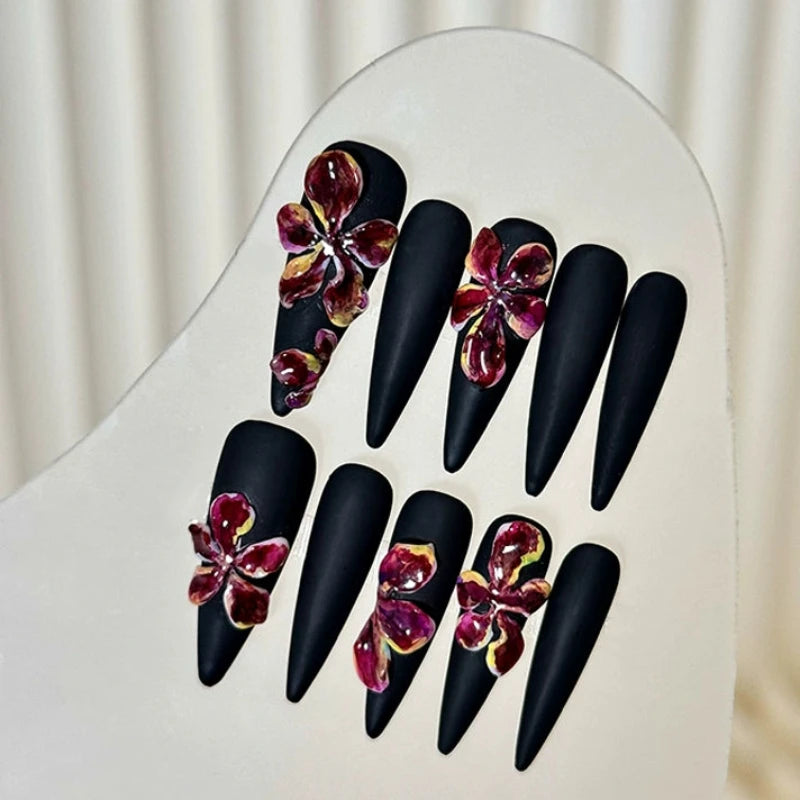 Elegant black stiletto nails with artistic floral details.