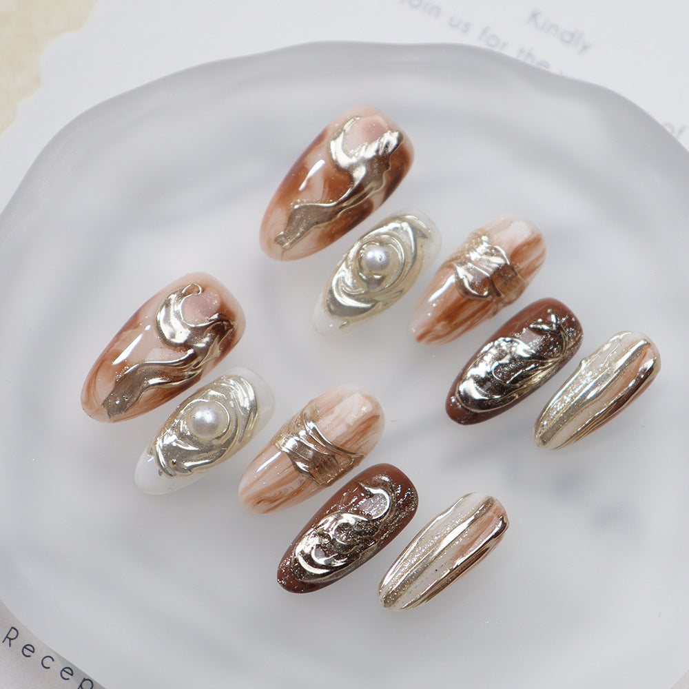 Hand-painted amber oval nails with gold and pearl details.