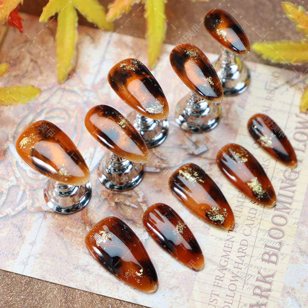 Elegant medium-length oval nails featuring autumn-inspired designs.