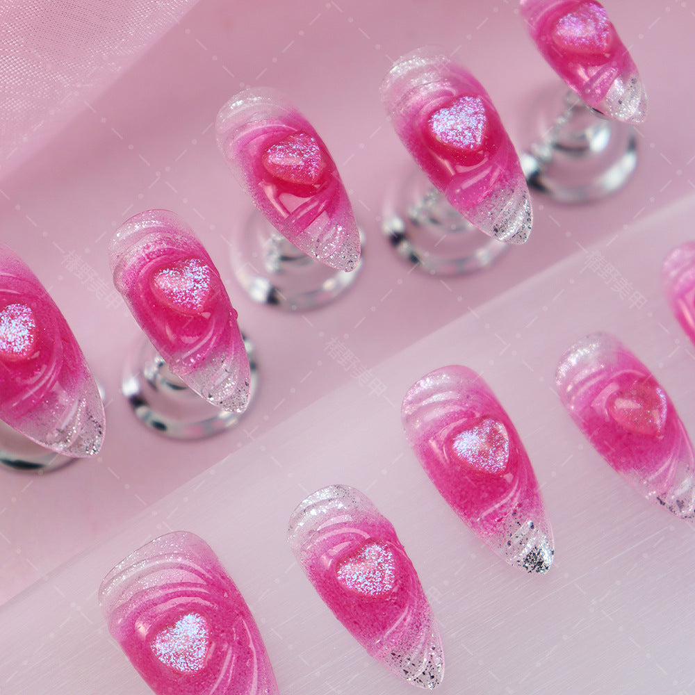 Close-up of pink gradient almond nails with heart-shaped accents.