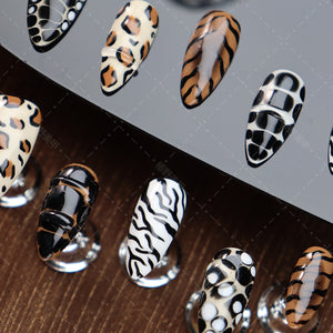 Almond-shaped nails with mixed animal patterns on a reflective surface.